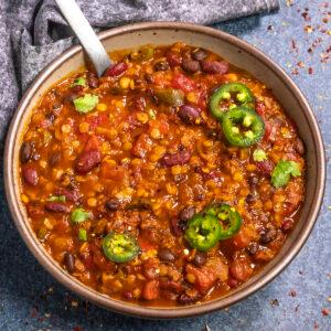 close up of lentils being poured into a pot of chili