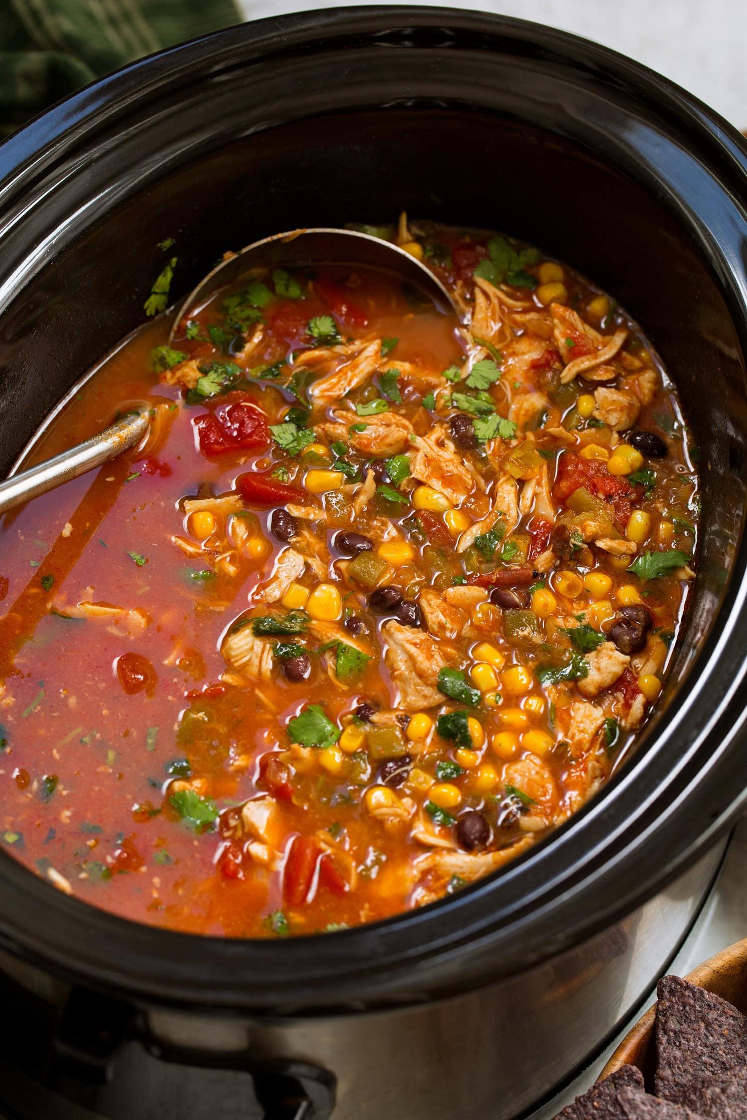 Close-up of a bowl of crockpot tortilla soup, steam rising