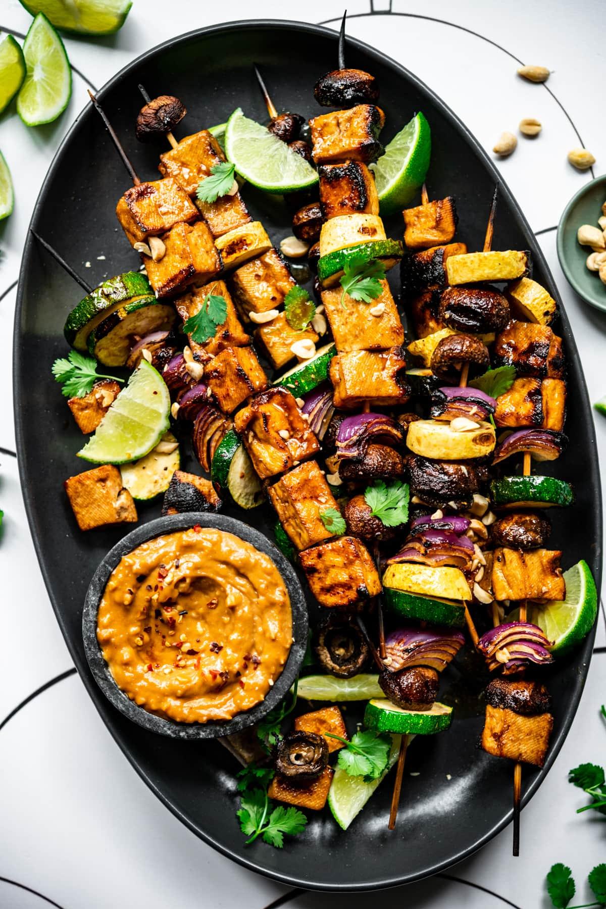 close-up shot of vegetable skewers being drizzled with peanut sauce