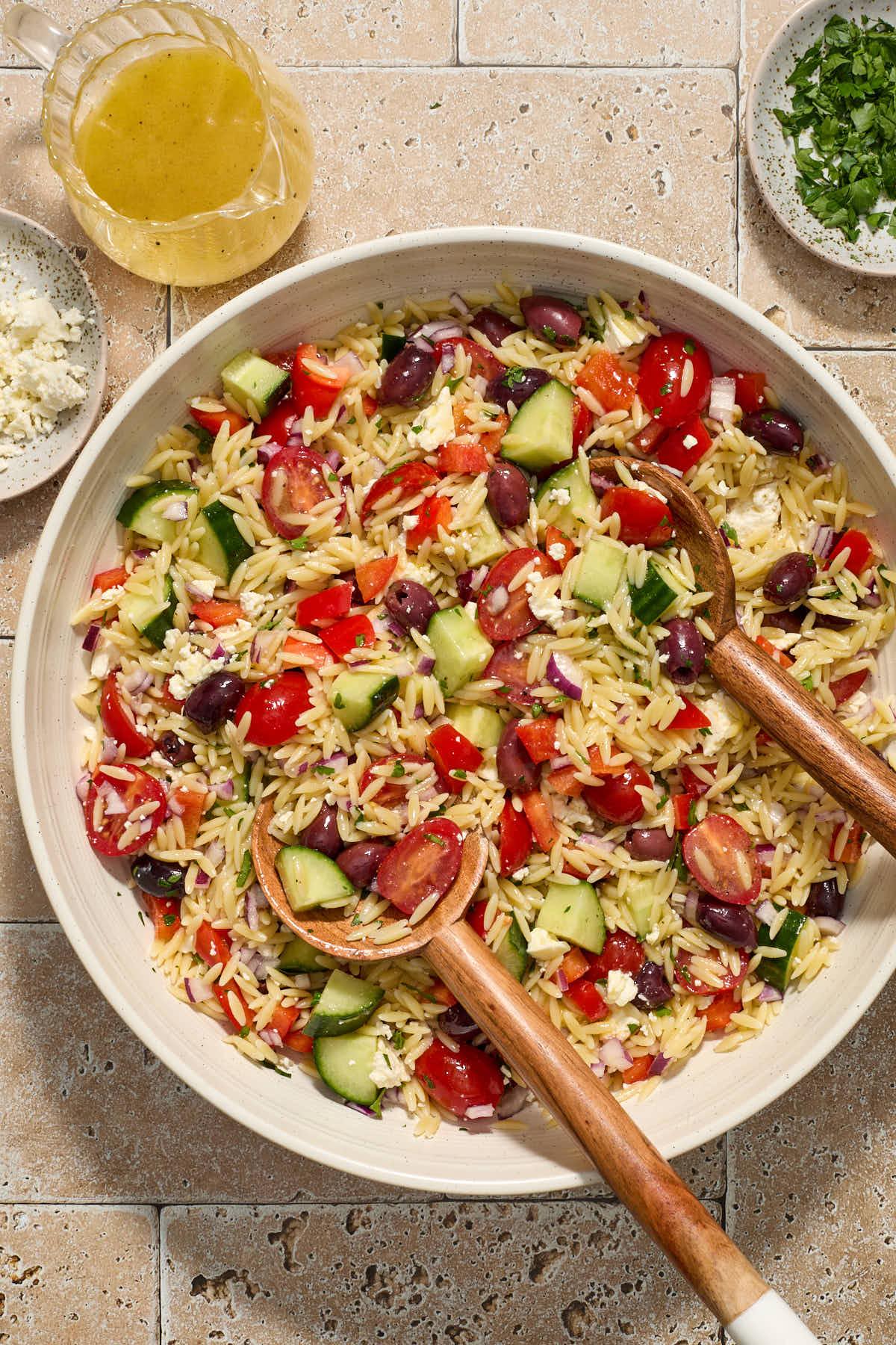 close up shot of Greek orzo pasta salad with lemon vinaigrette in a white bowl