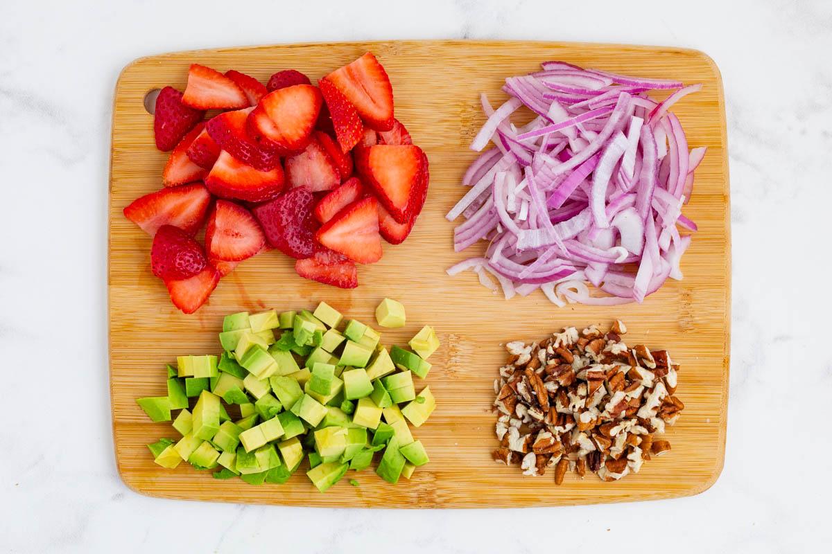 ingredients for strawberry spinach salad arranged on a wooden board