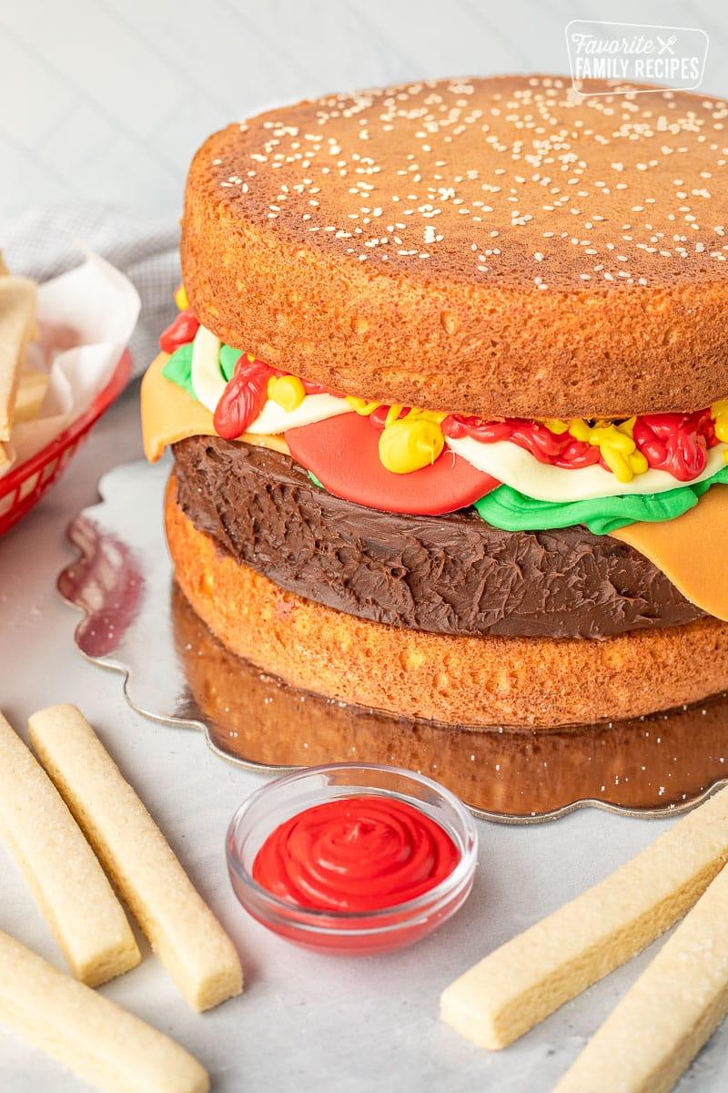 Close-up of a sliced burger cake showing layers of vanilla and chocolate cake with frosting