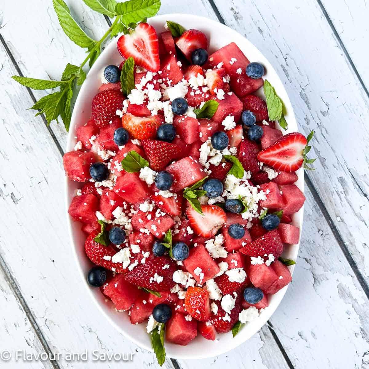 overhead shot of watermelon strawberry salad in a clear glass bowl