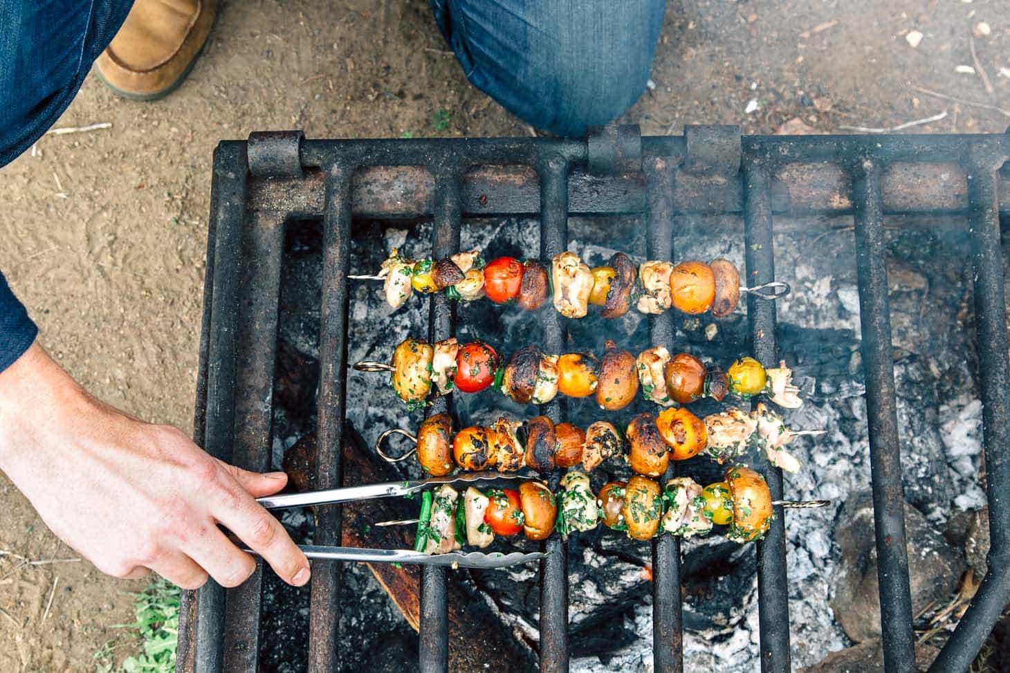 family grilling chicken skewers in backyard