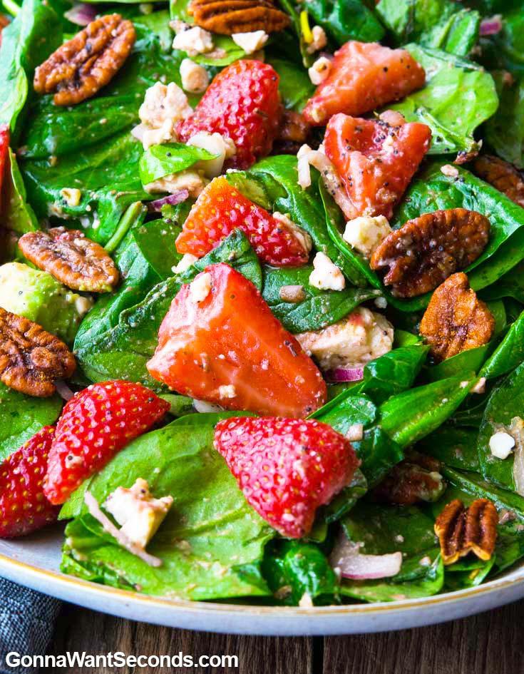 close-up of strawberry spinach salad being tossed