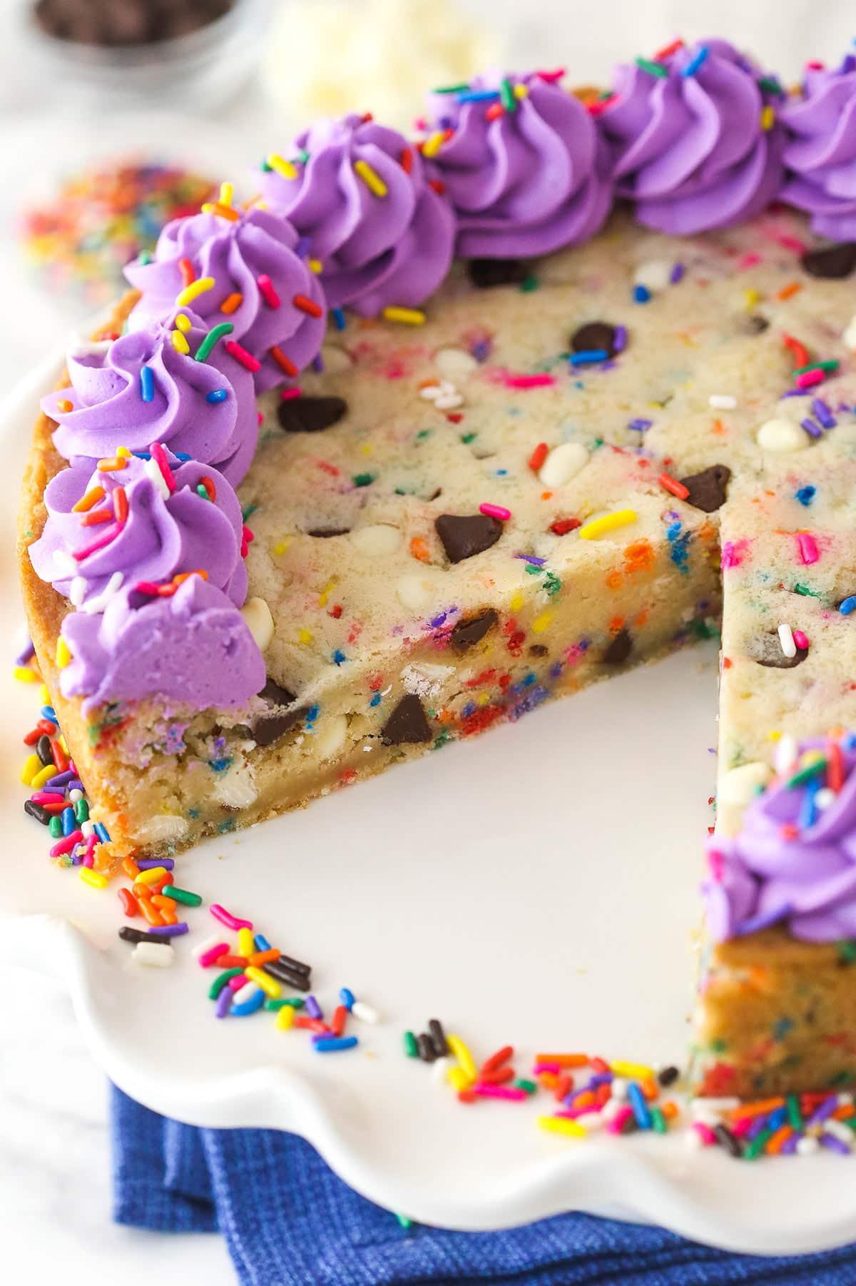 A close up shot of decorating the graduation cookie cake with various sprinkles and candies