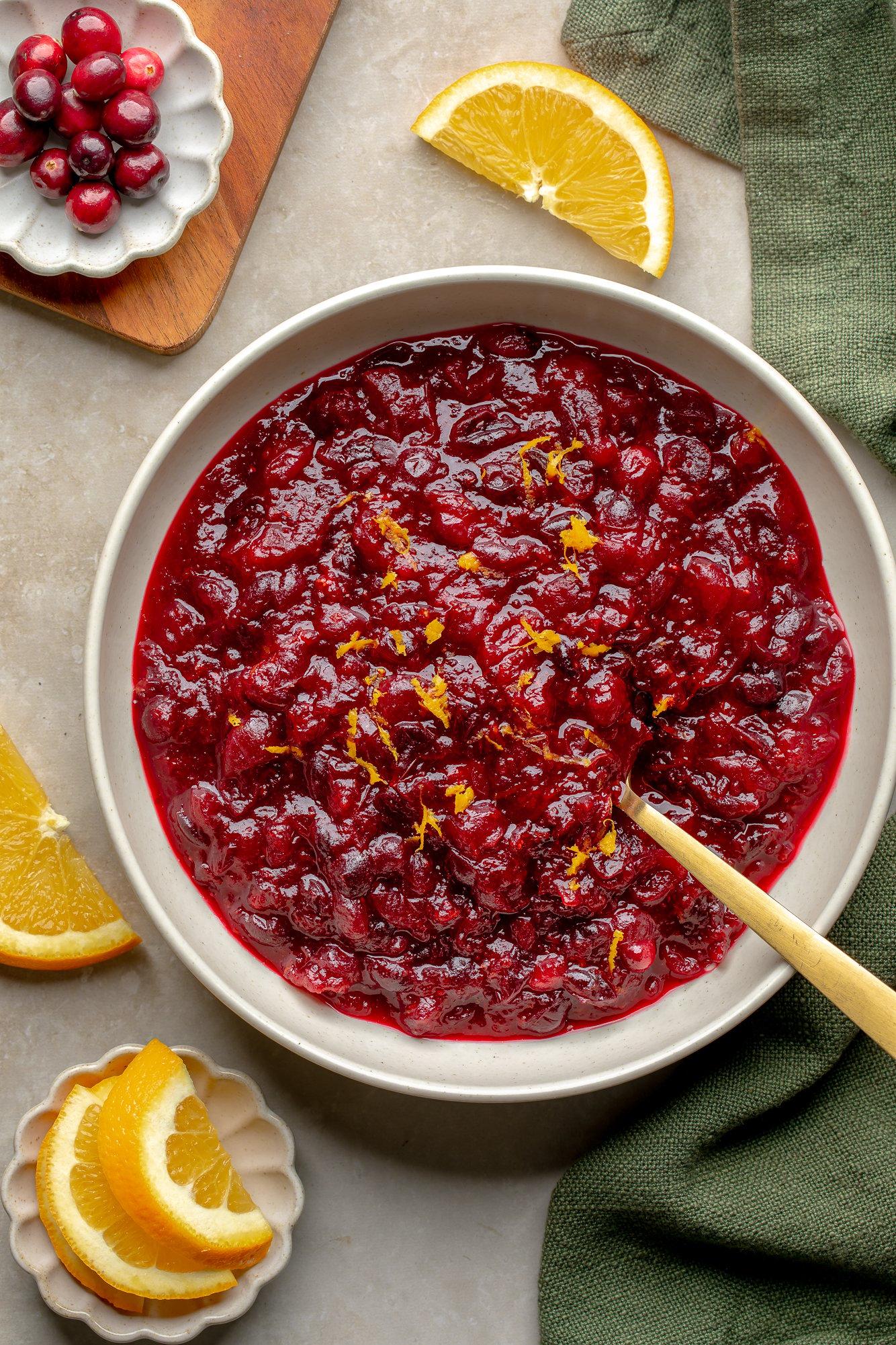 Vibrant homemade cranberry orange sauce in a serving bowl with fresh cranberries and orange slices