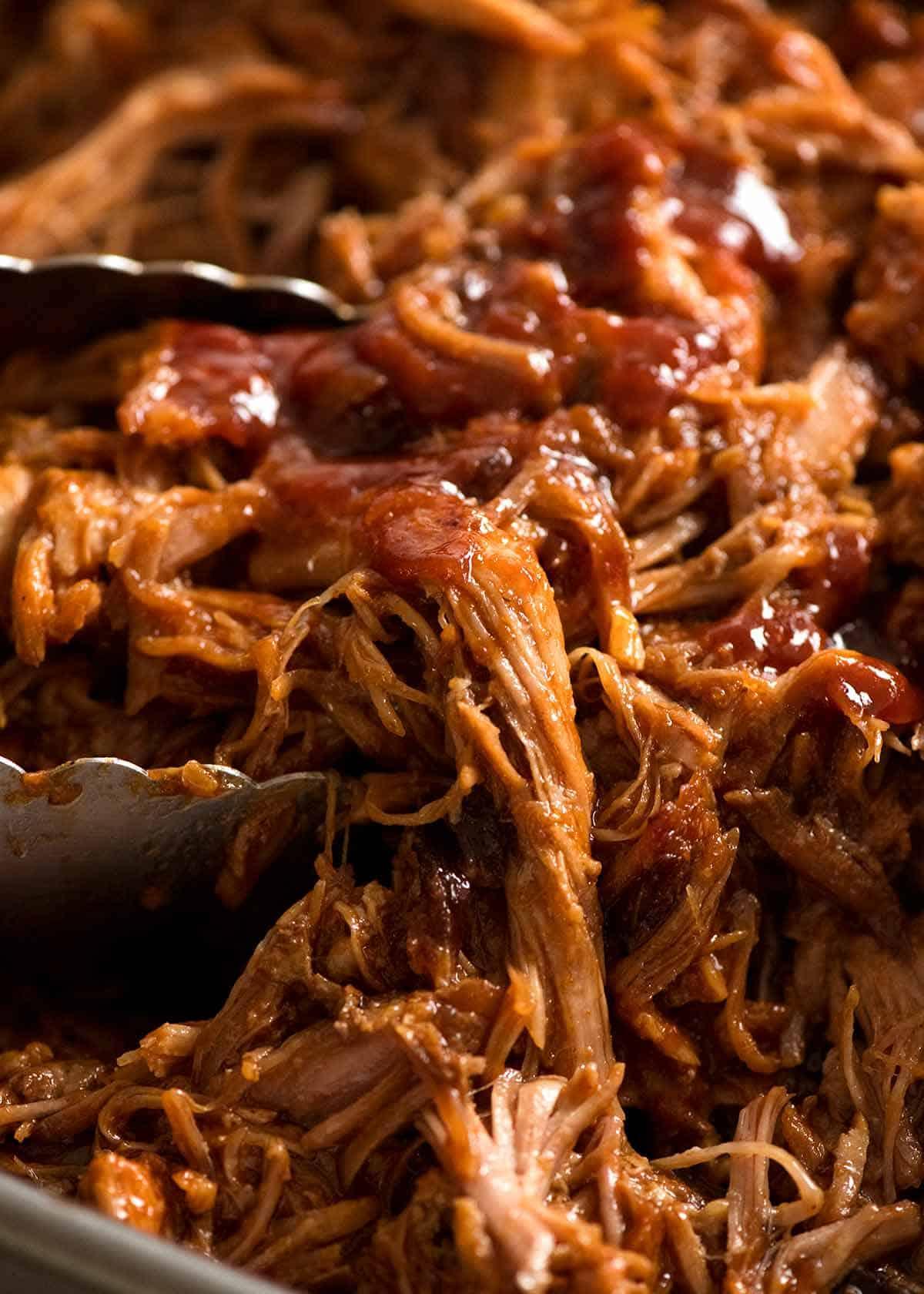 Close-up shot of pulled pork being mixed with barbecue sauce