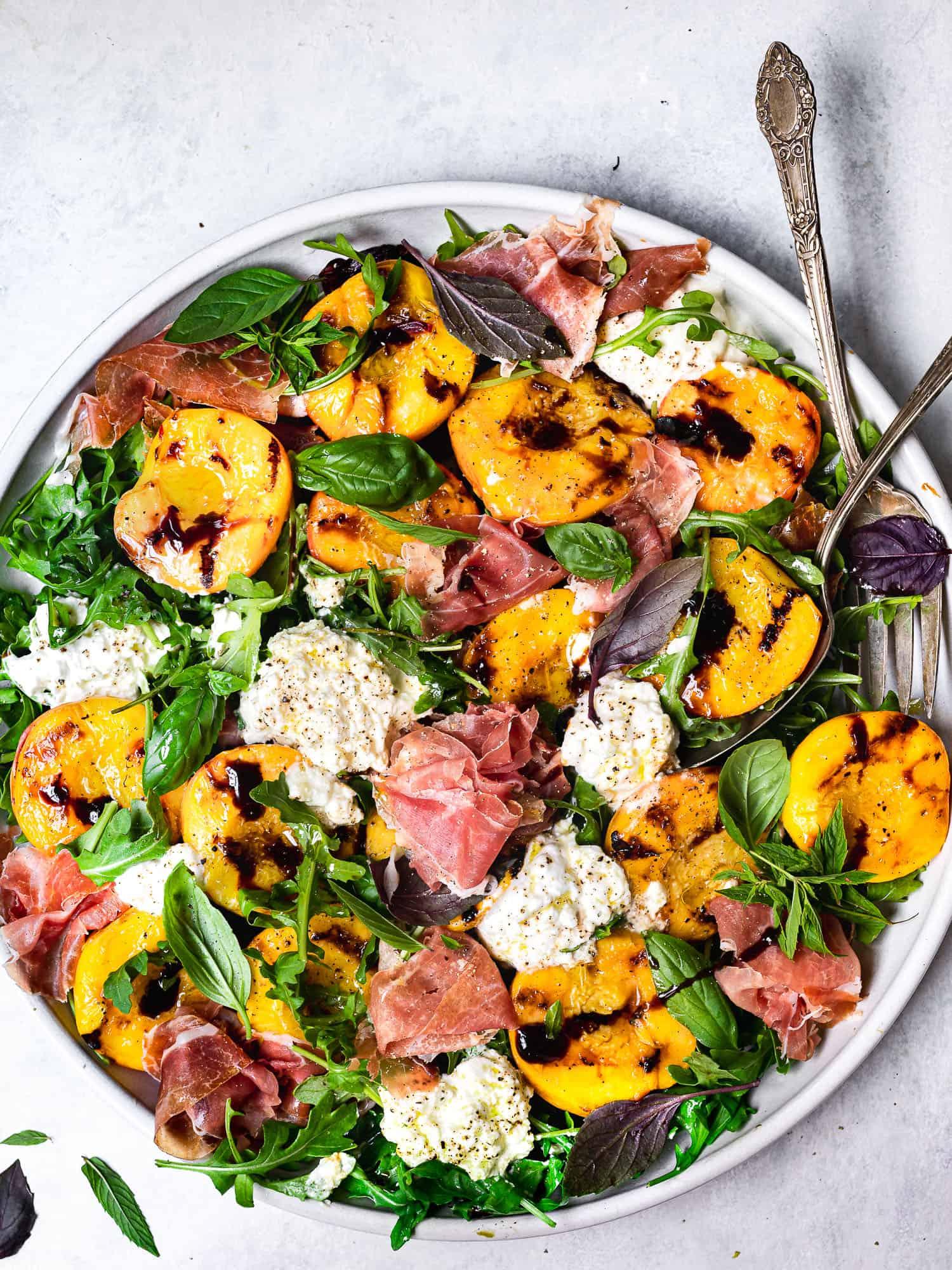 overhead shot of grilled peach and burrata salad with balsamic reduction and fresh basil