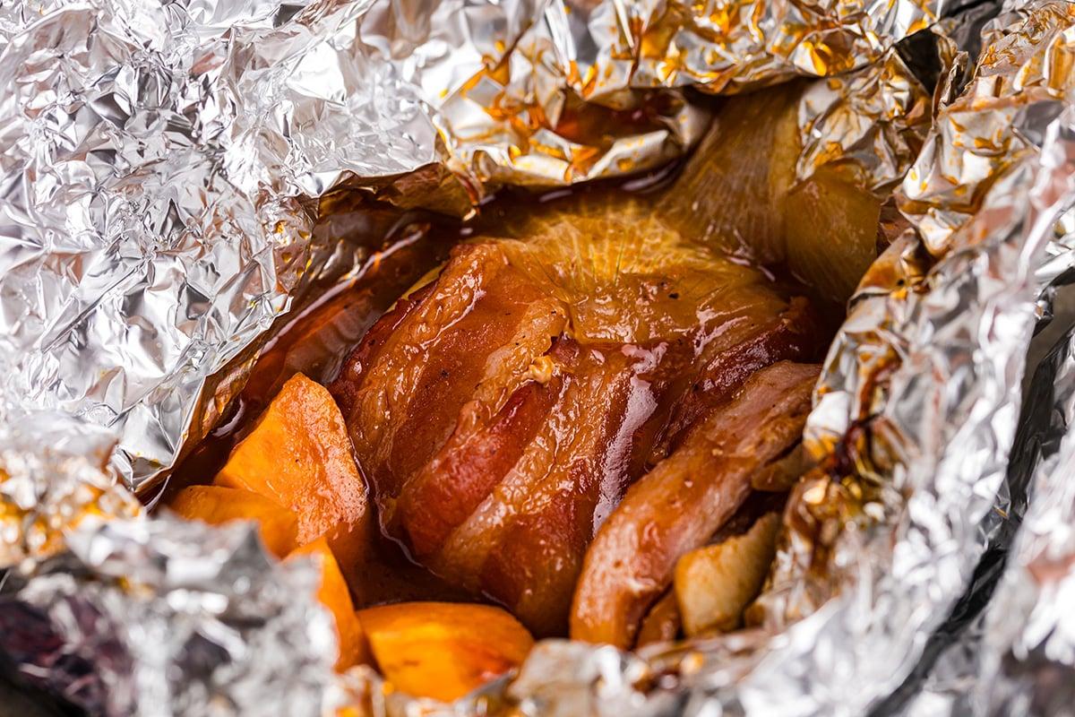 Close-up of a foil packet being opened to reveal cooked chicken