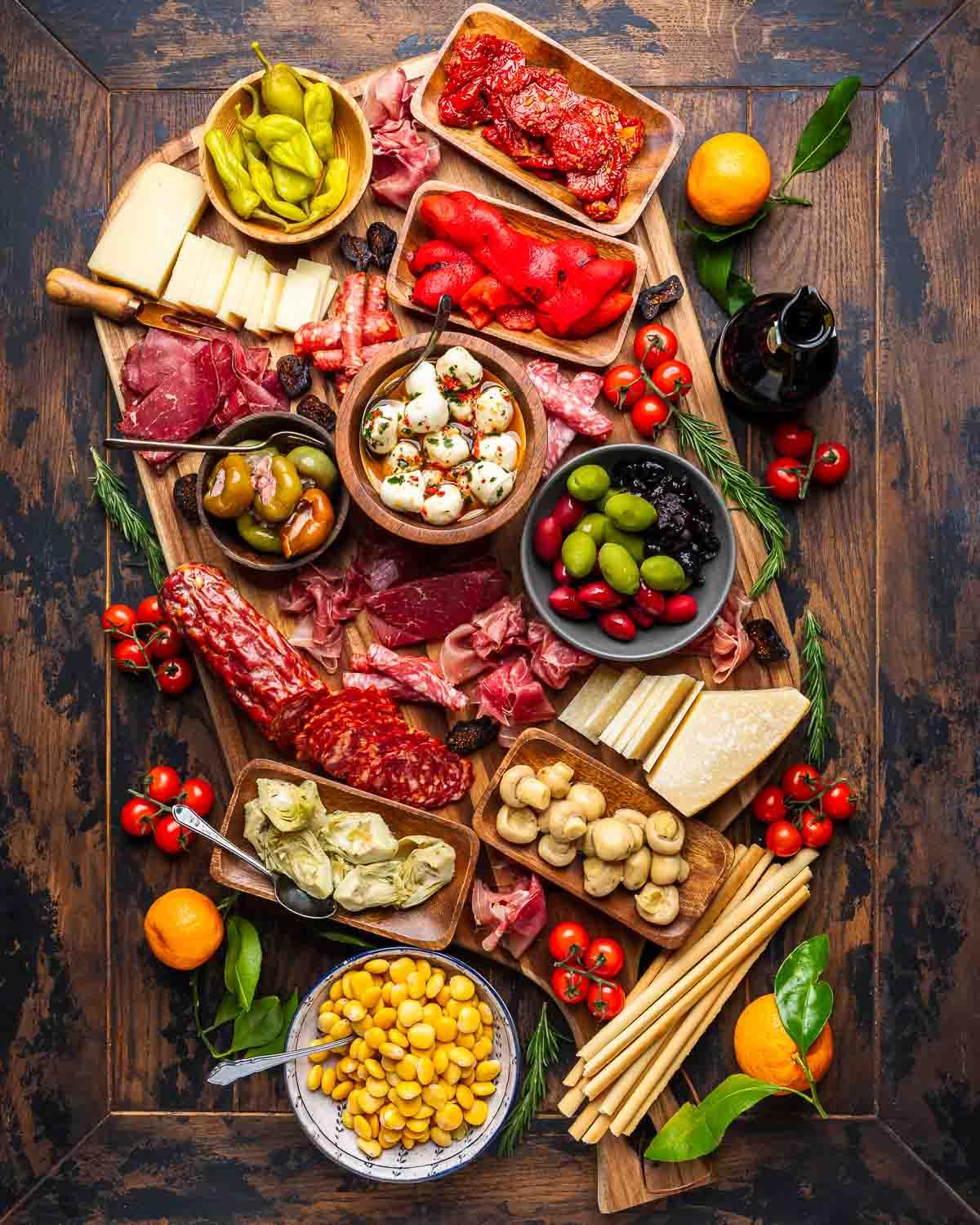 Ingredients for a mediterranean cheese and antipasto spread arranged on a wooden table
