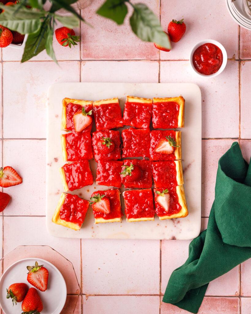 Overhead shot of several Maple Pecan Strawberry Cheesecake Bars arranged on a wooden board