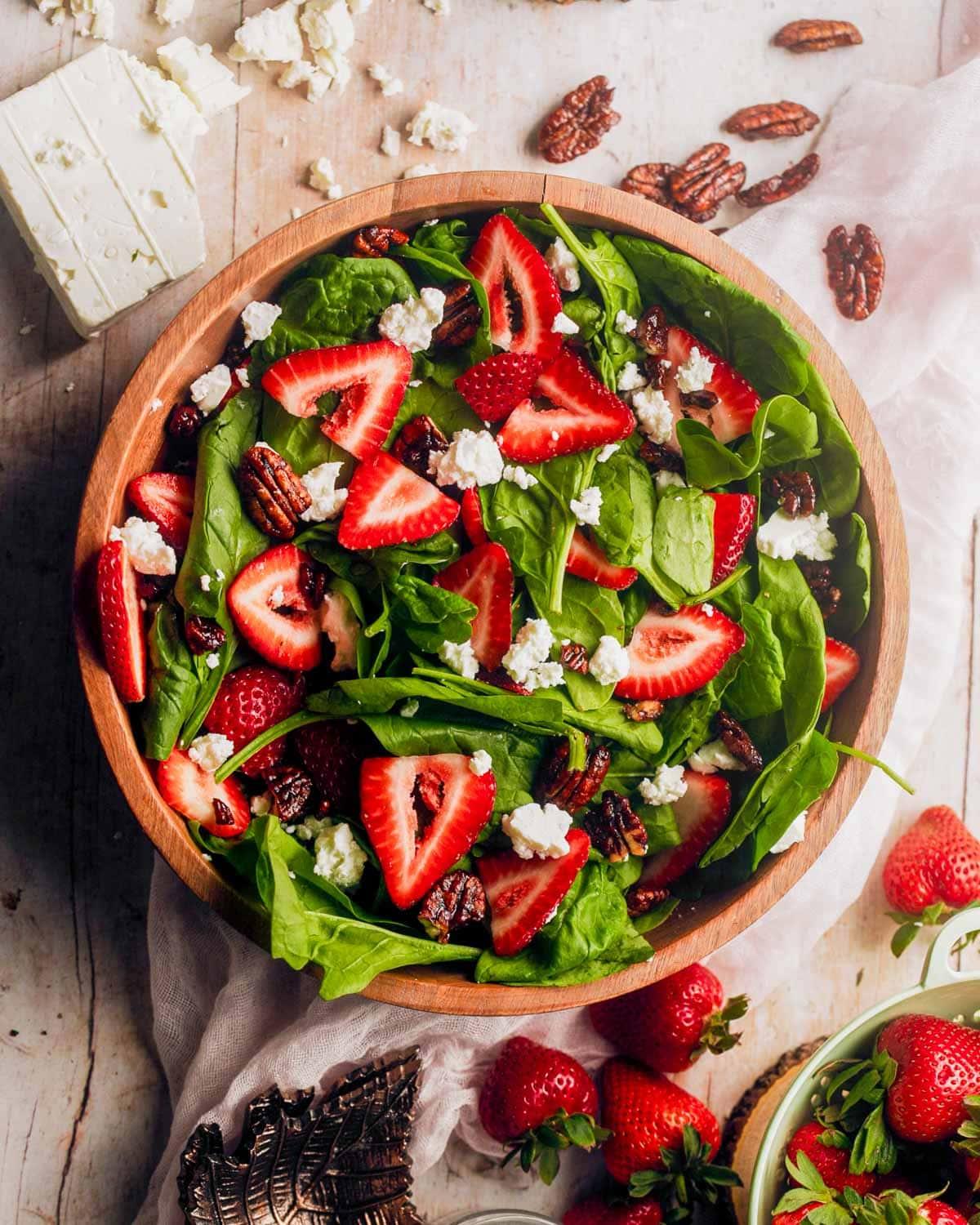 overhead shot of a large bowl of strawberry feta salad being tossed