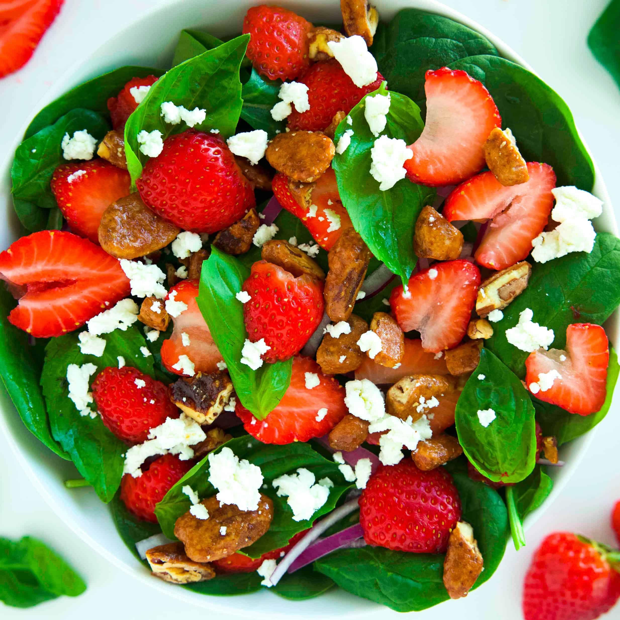 a vibrant bowl of strawberry spinach salad on a picnic blanket