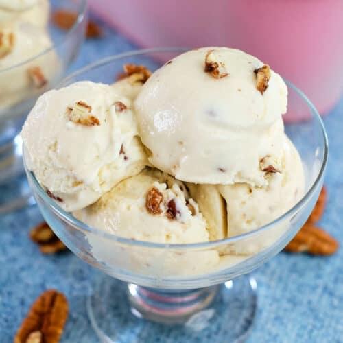 creamy maple pecan lassi in a glass with pecans and maple syrup drizzled on top