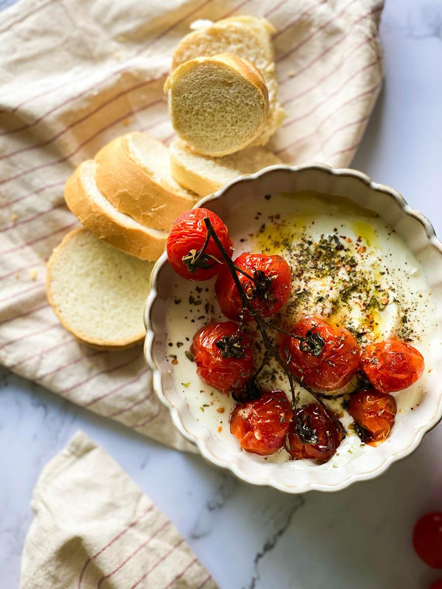close up shot of whipped feta dip with roasted cherry tomatoes and pita bread