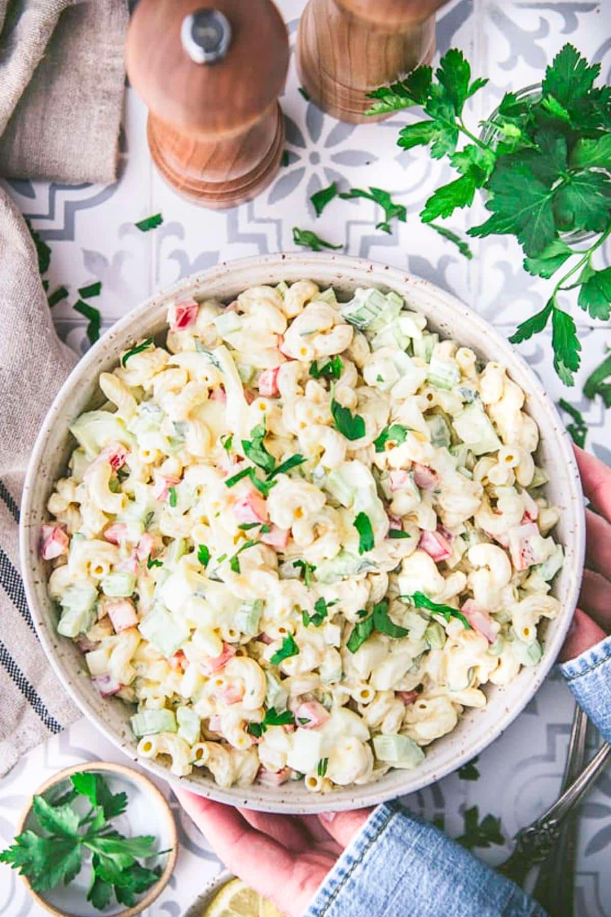 Overhead shot of a large bowl of macaroni salad being served at a picnic