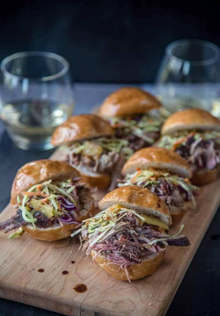 several pineapple bbq glazed ham sliders arranged on a platter with a side of coleslaw