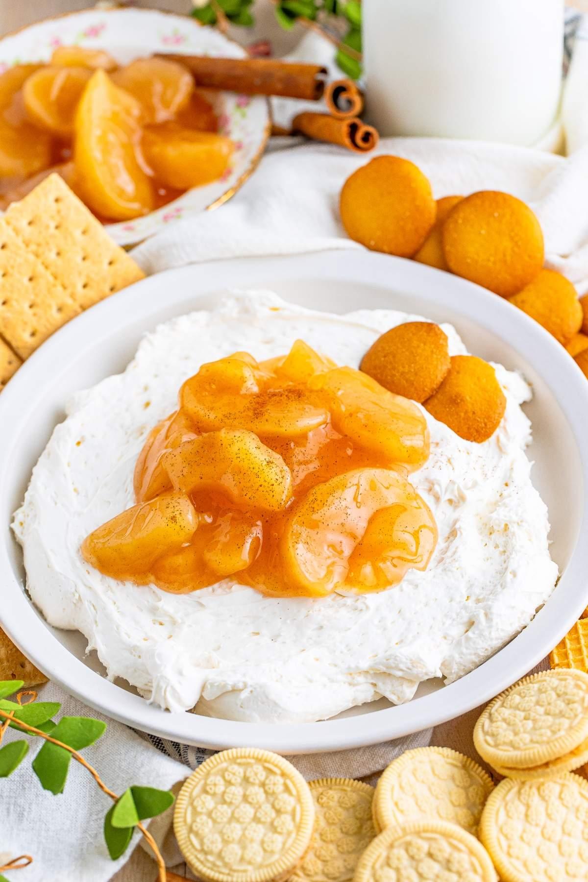 creamy snickerdoodle cheesecake dip in a white bowl surrounded by graham crackers and apple slices
