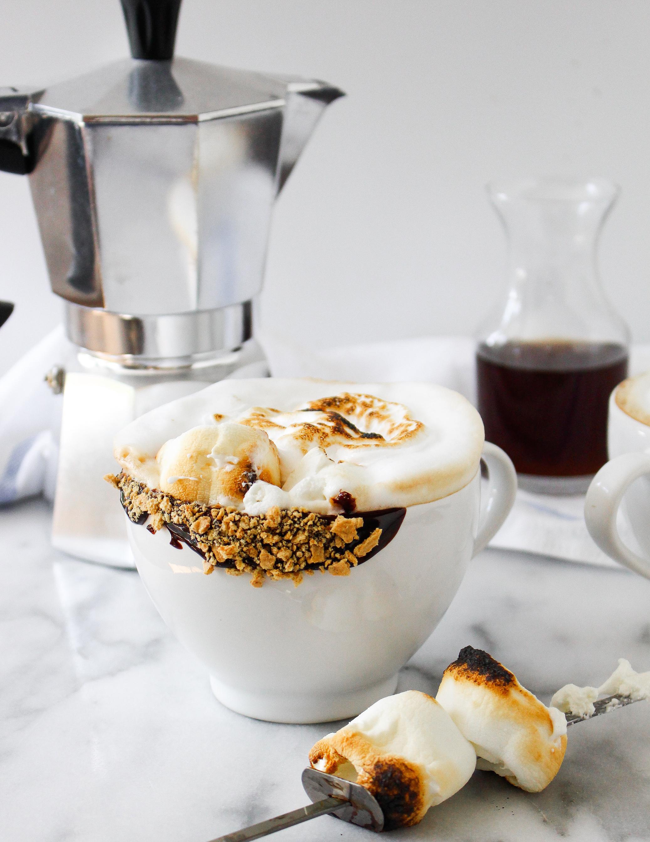 person toasting marshmallows over a gas stovetop with chai latte ingredients in the background