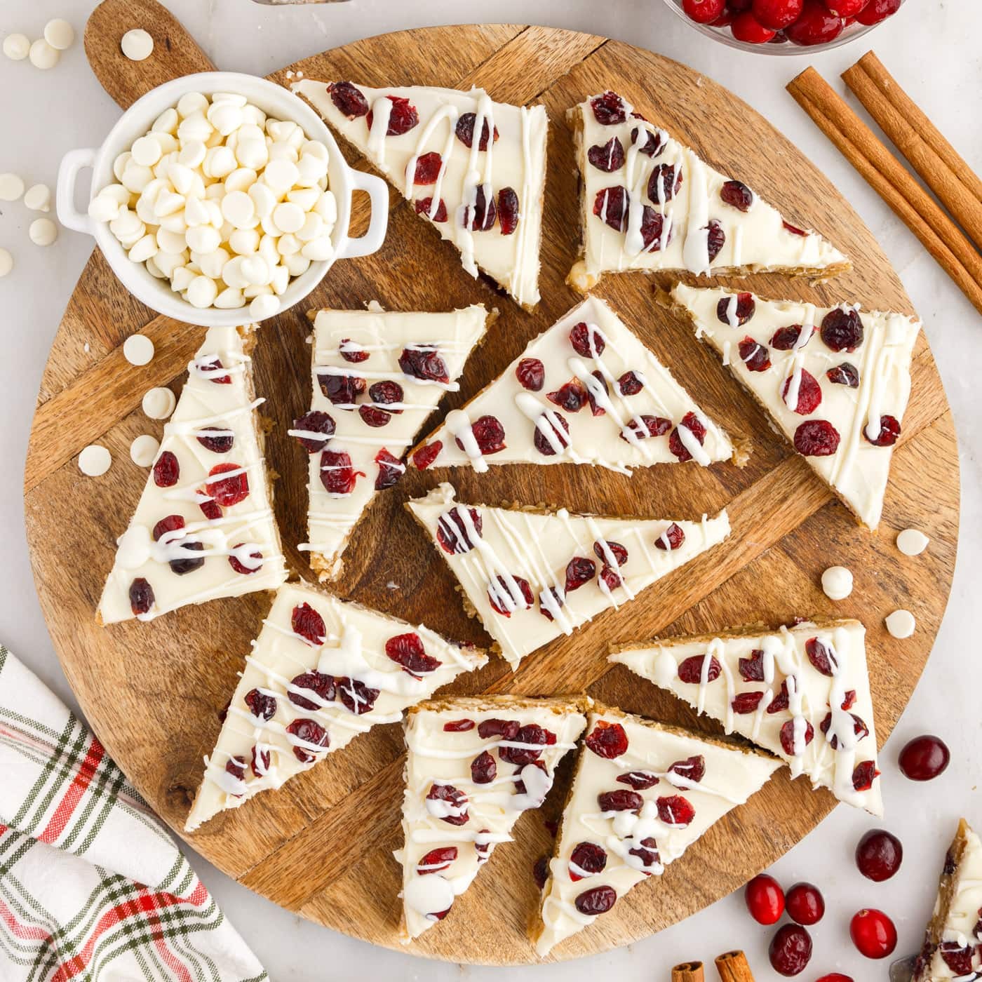 festive white chocolate cranberry bliss bars on a rustic wooden platter with holiday decor