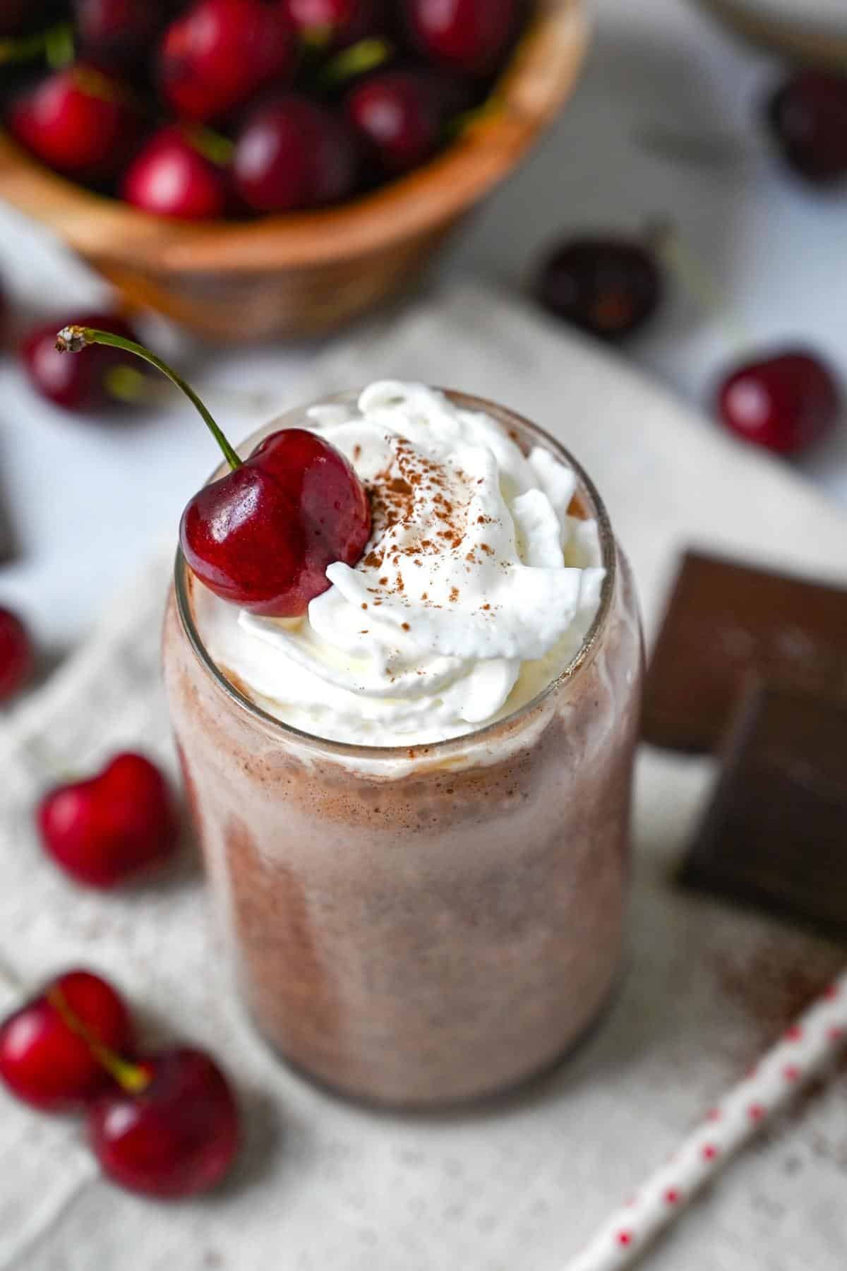 cherry chocolate protein smoothie with whipped cream and chocolate shavings