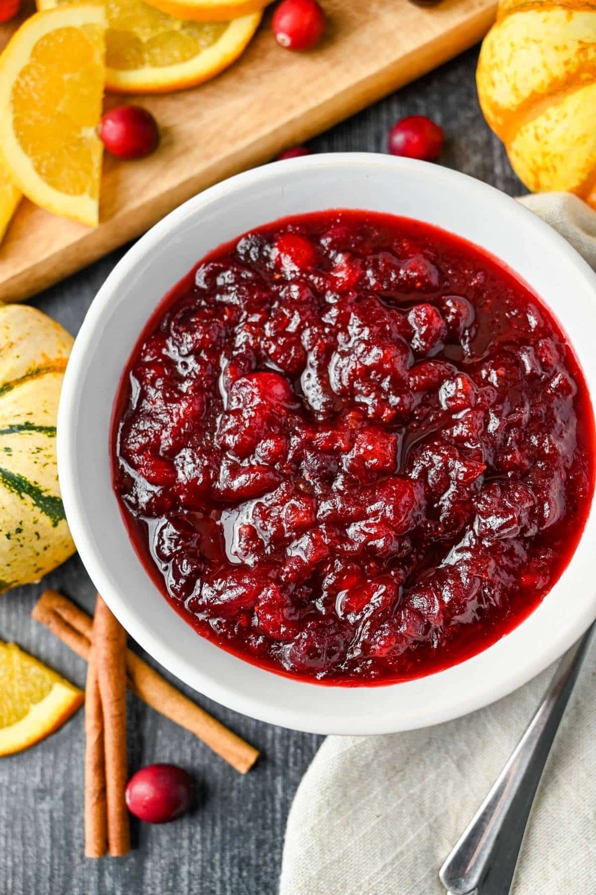 close-up homemade cranberry sauce in a rustic bowl with fresh cranberries and orange zest