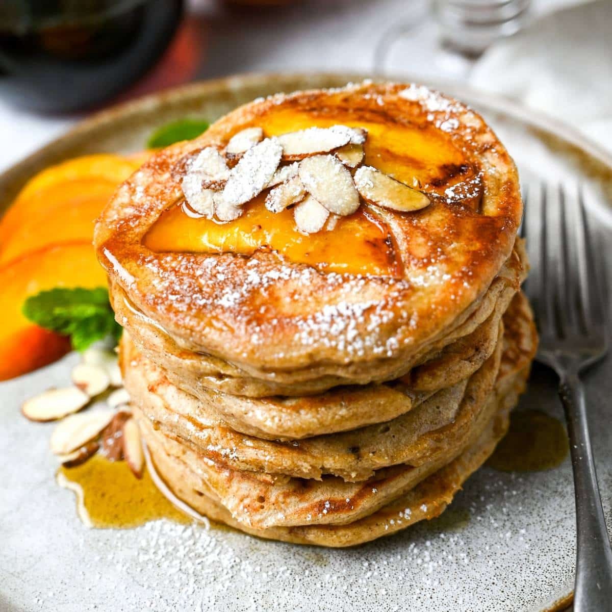 stack of peach cobbler gluten-free pancakes with fresh peaches and syrup