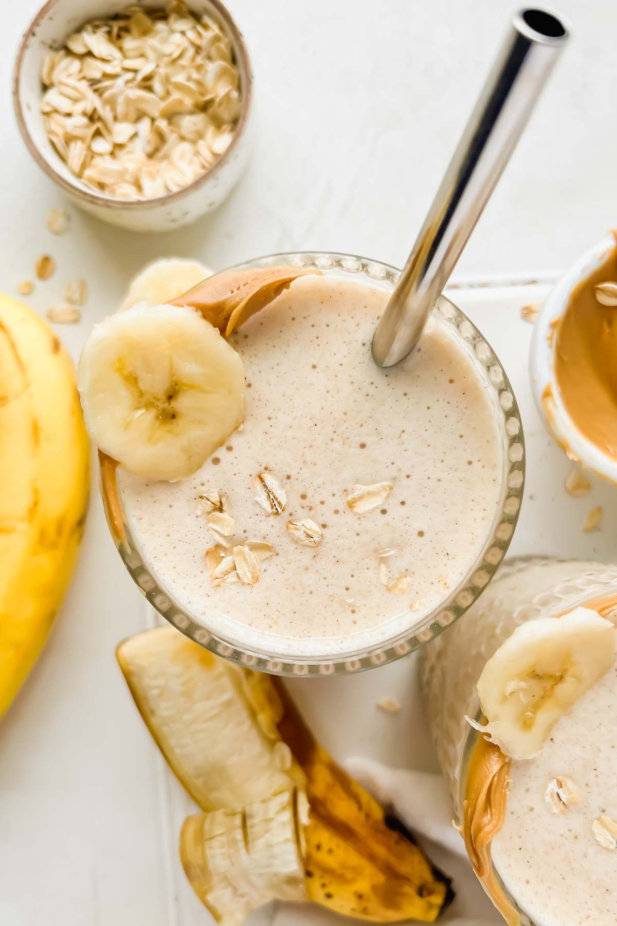 a glass of banana bread smoothie with banana slices and nuts on top