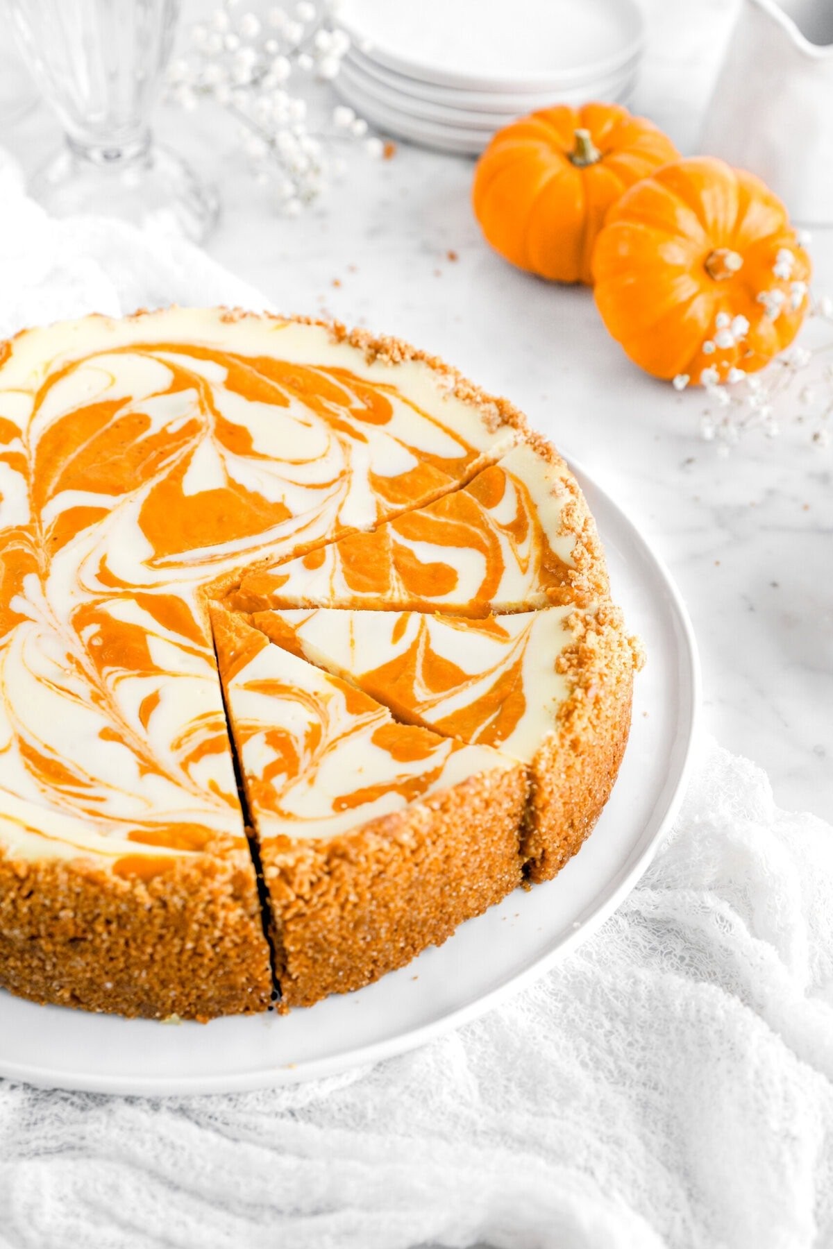 Pumpkin cheesecake with creamy white swirl on a rustic table with autumn leaves