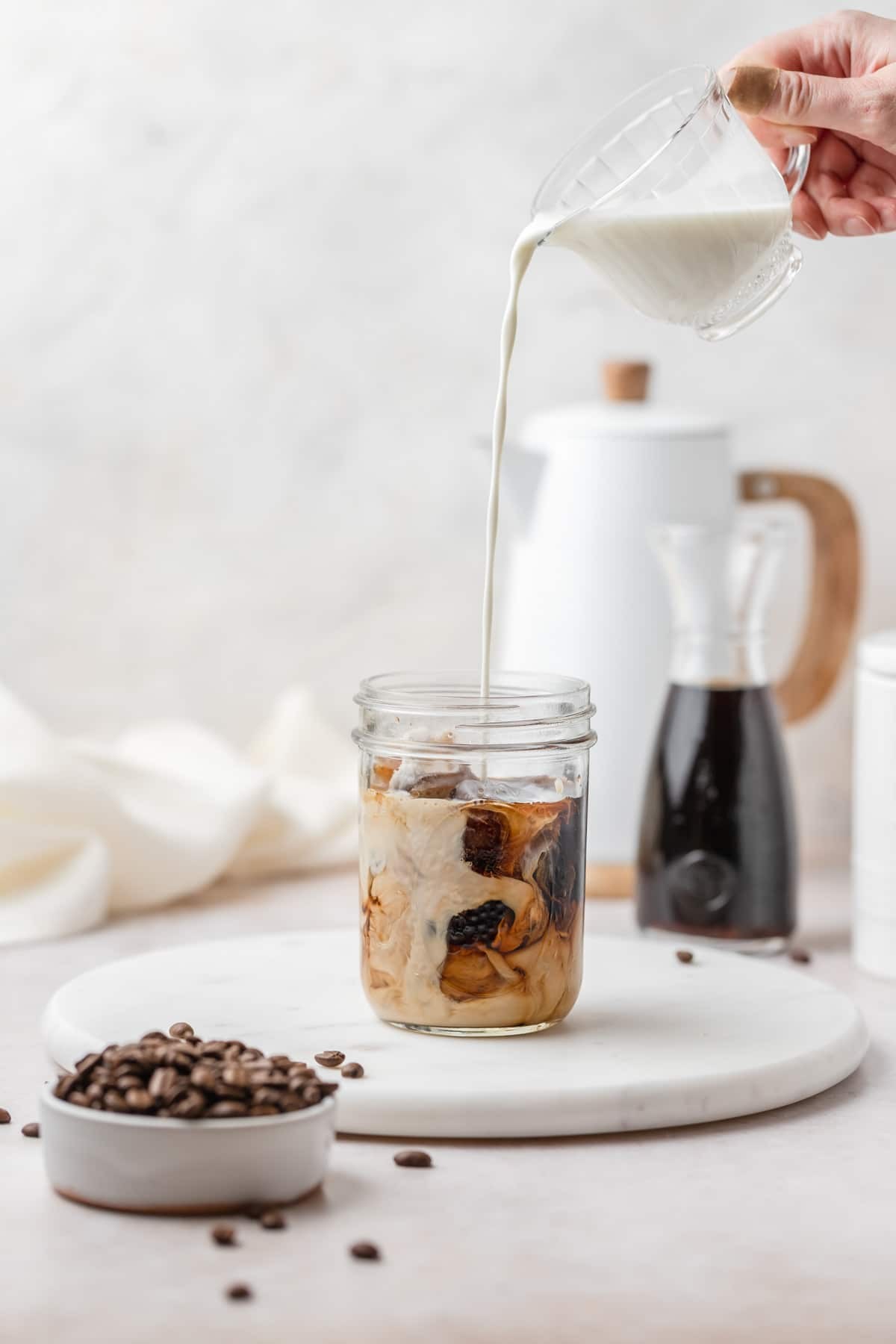 glass of vanilla bean cold brew with vanilla beans and coffee beans