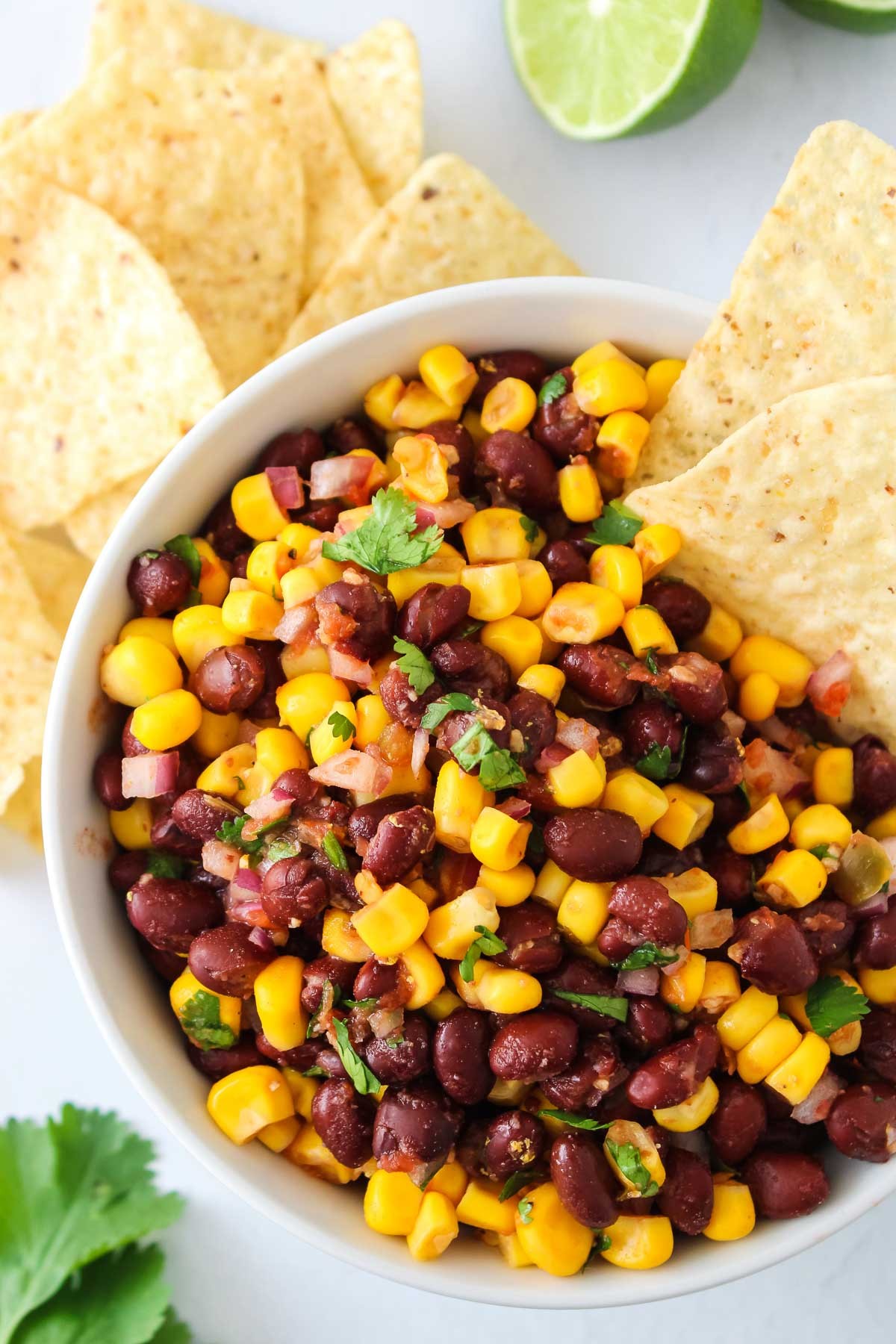 fresh black bean and corn salsa with lime tortilla chips on a wooden table