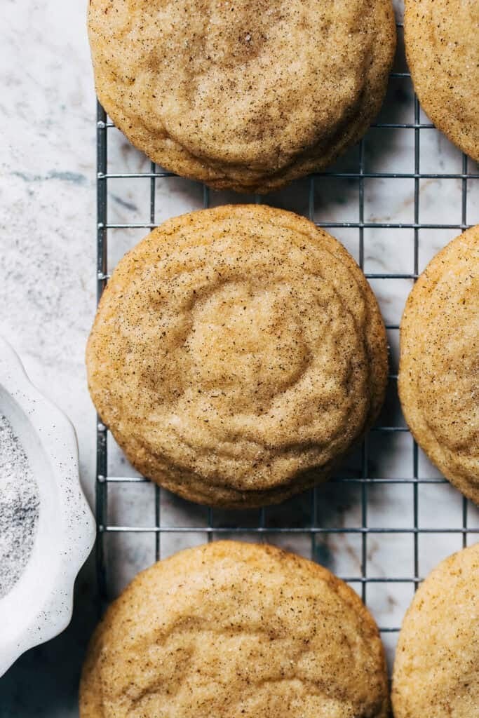 Close-up of golden-brown sugar cookies with visible vanilla bean specks, on a rustic cooling rack