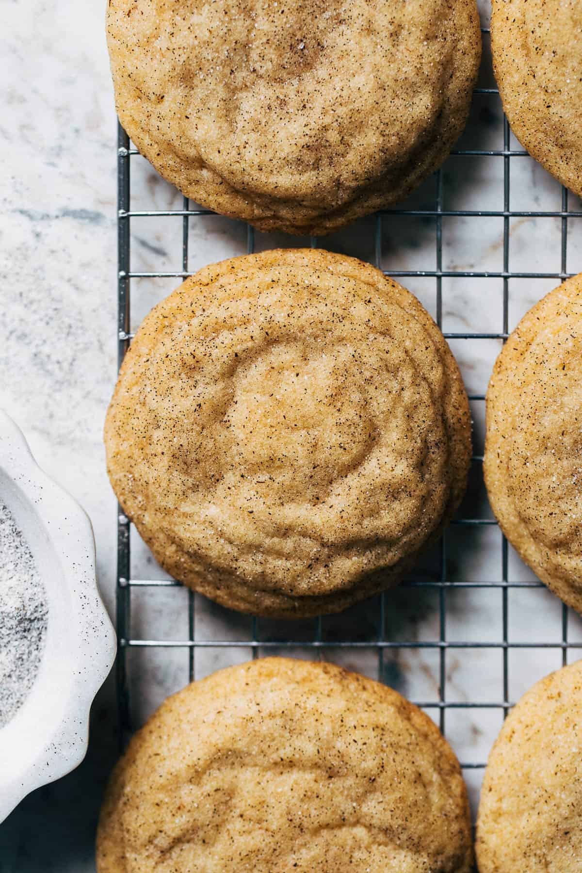 Close-up of golden sugar cookies with visible vanilla bean specks on a cooling rack, natural light