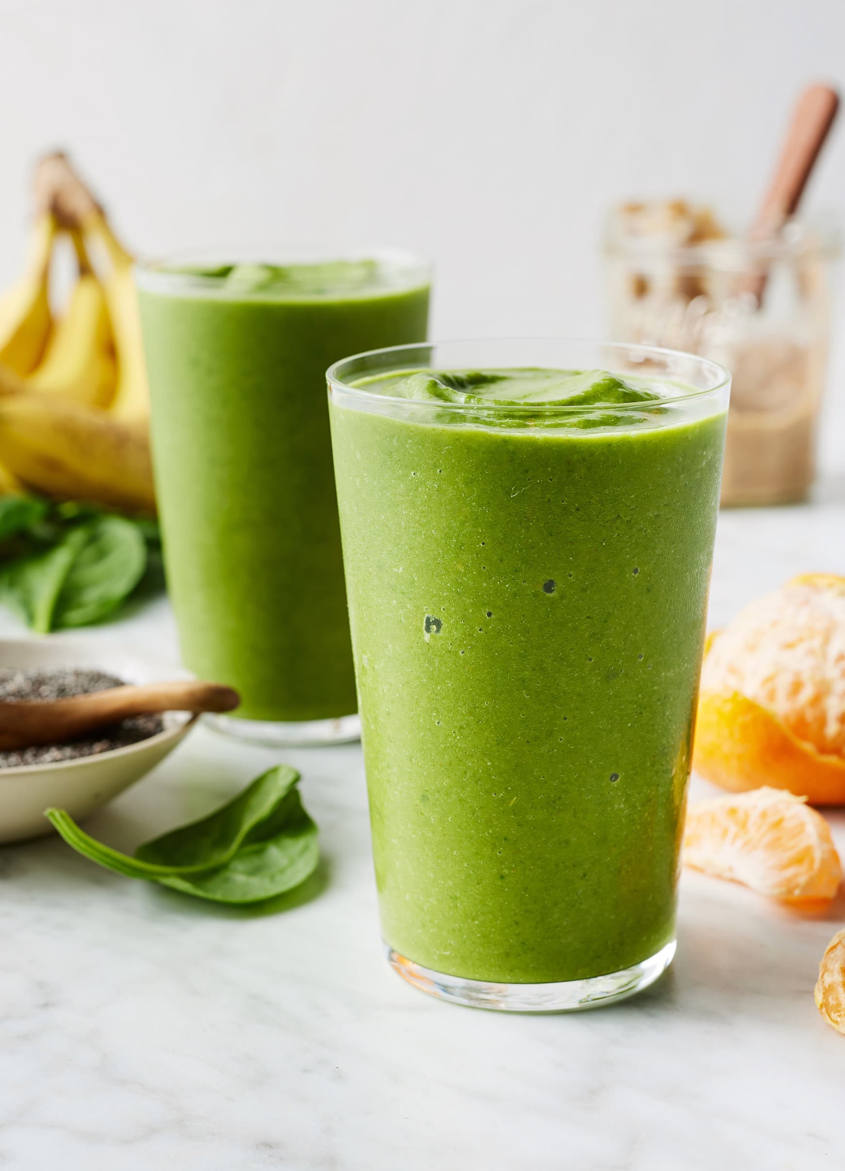 vibrant green smoothie in a glass with spinach, banana, and almond milk