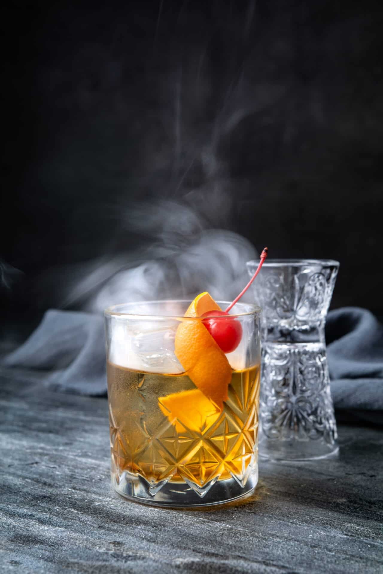 a perfectly garnished Old Fashioned cocktail on a dimly lit bar