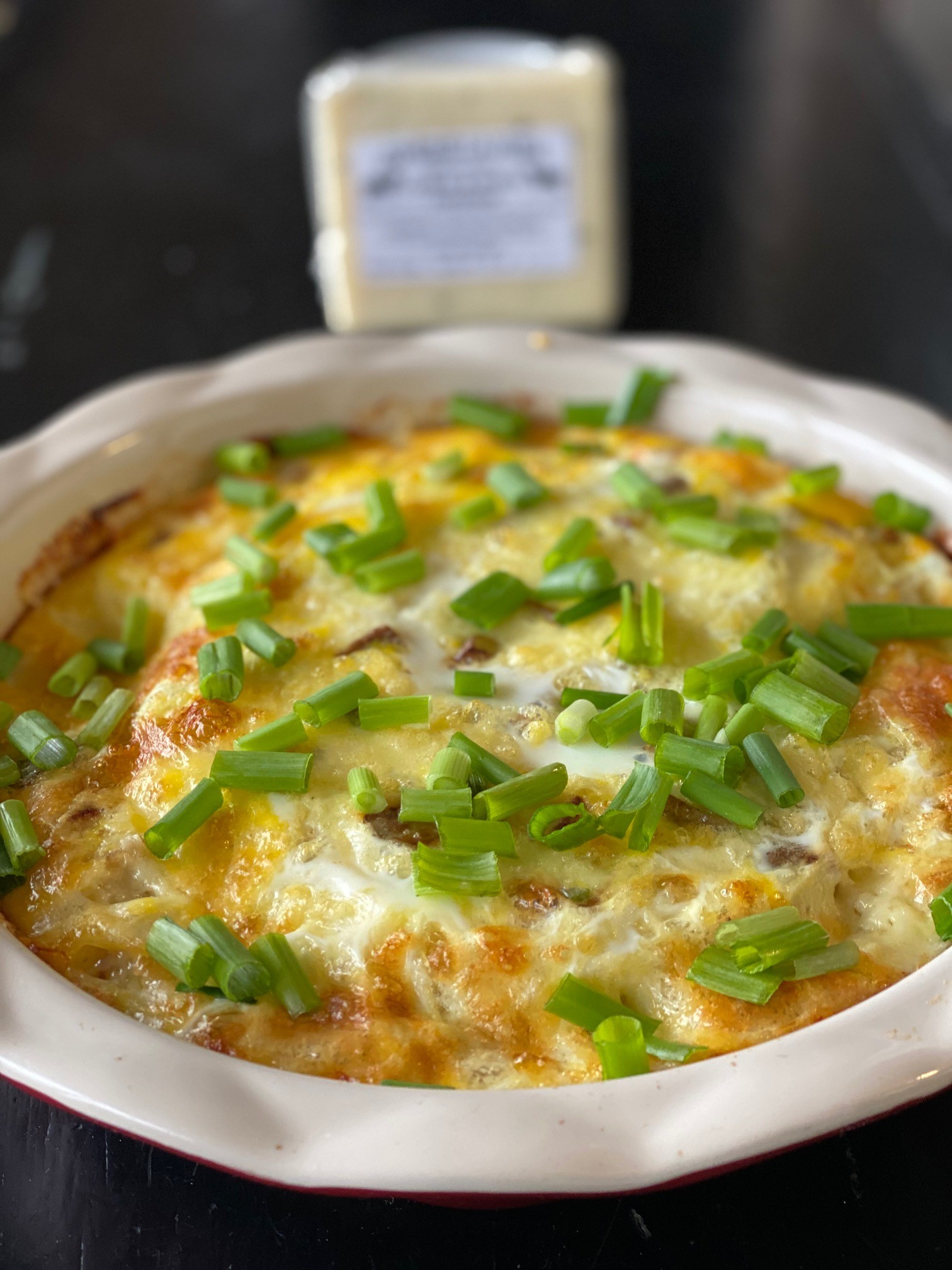 Delicious golden cheesy egg bake casserole, warm and steaming, fresh out of the oven, garnished with chives