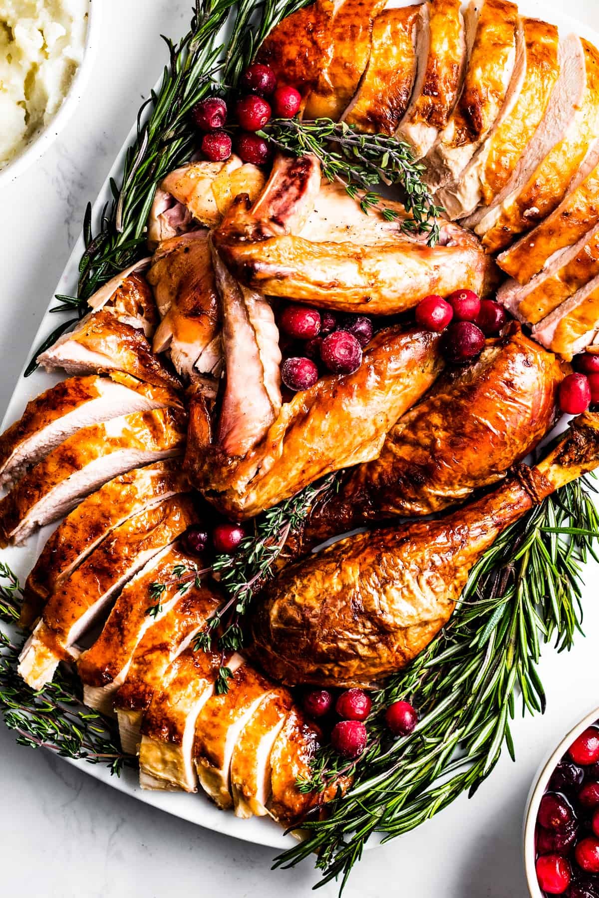 whole oven roasted turkey with crispy skin garnished with fresh rosemary and cranberries on a platter, warm inviting light, holiday setting