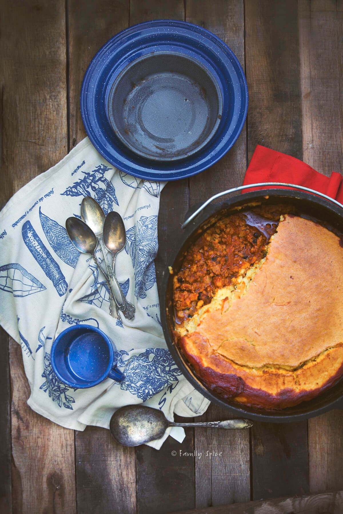 Rustic deep-red chili in a cast iron pot, steam rising, with crusty bread on the side