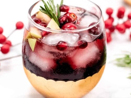 vibrant ruby red sangria with festive garnishes in crystal glasses, holiday party background, warm lighting