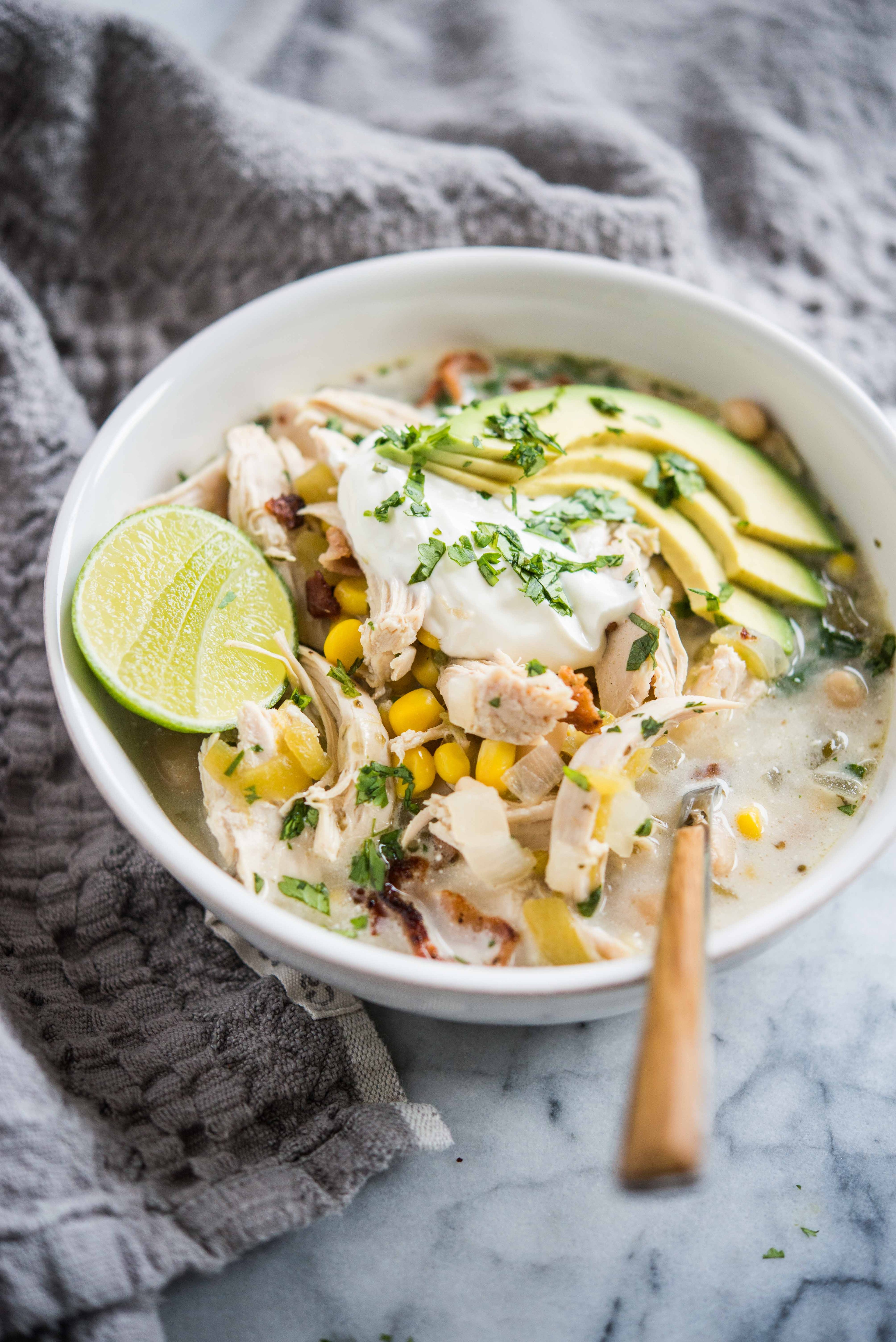 comforting bowl of white chili cream chicken, garnished with cilantro and sour cream