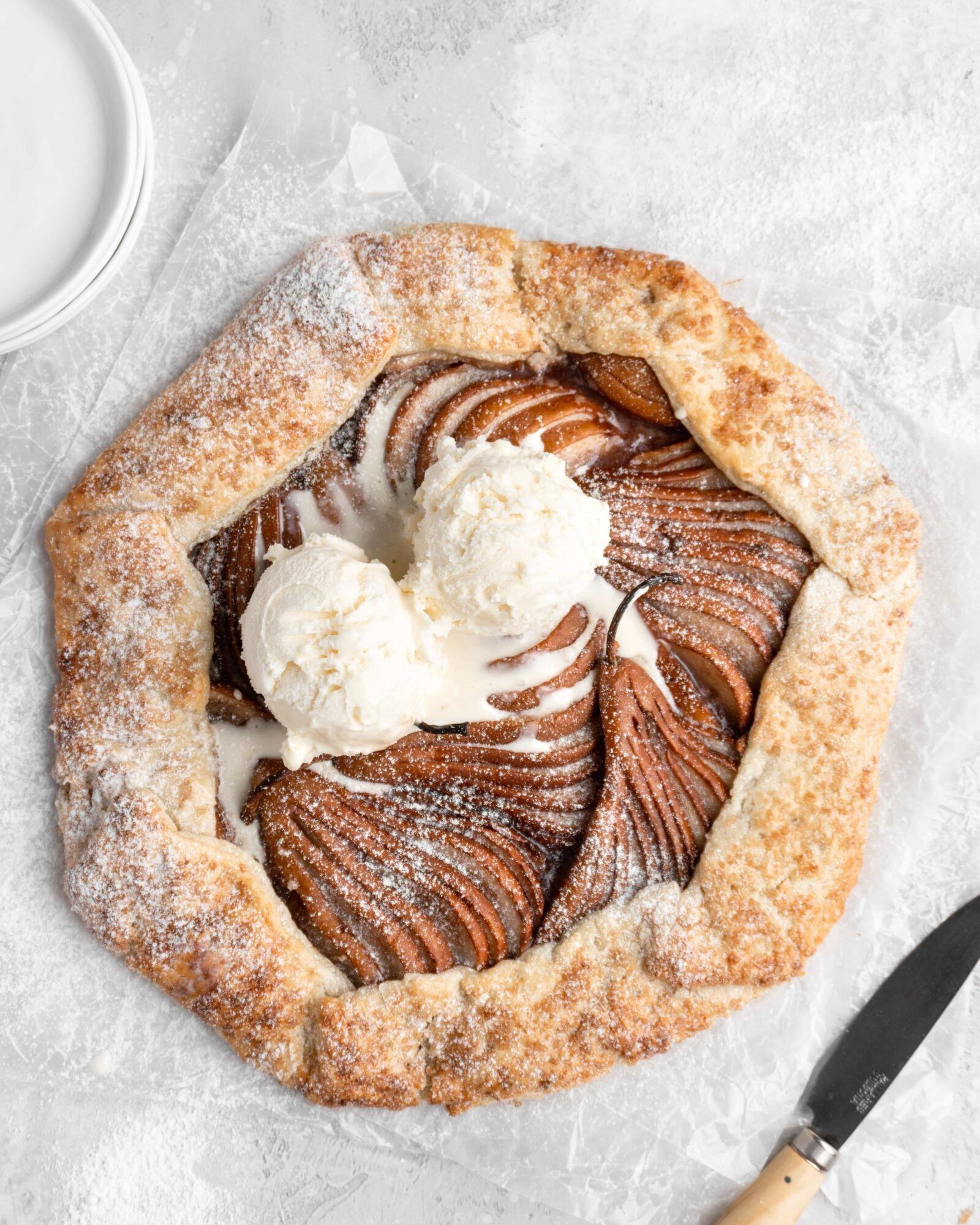 Spiced pear galette on a wooden cutting board, rustic kitchen setting