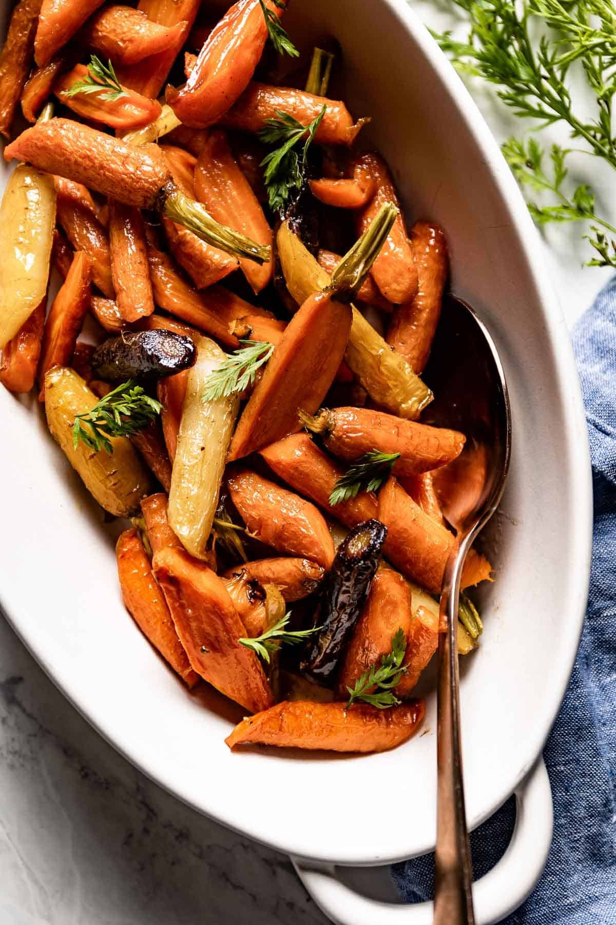 Roasted sweet maple glazed carrots in a serving dish, festive Thanksgiving table setting