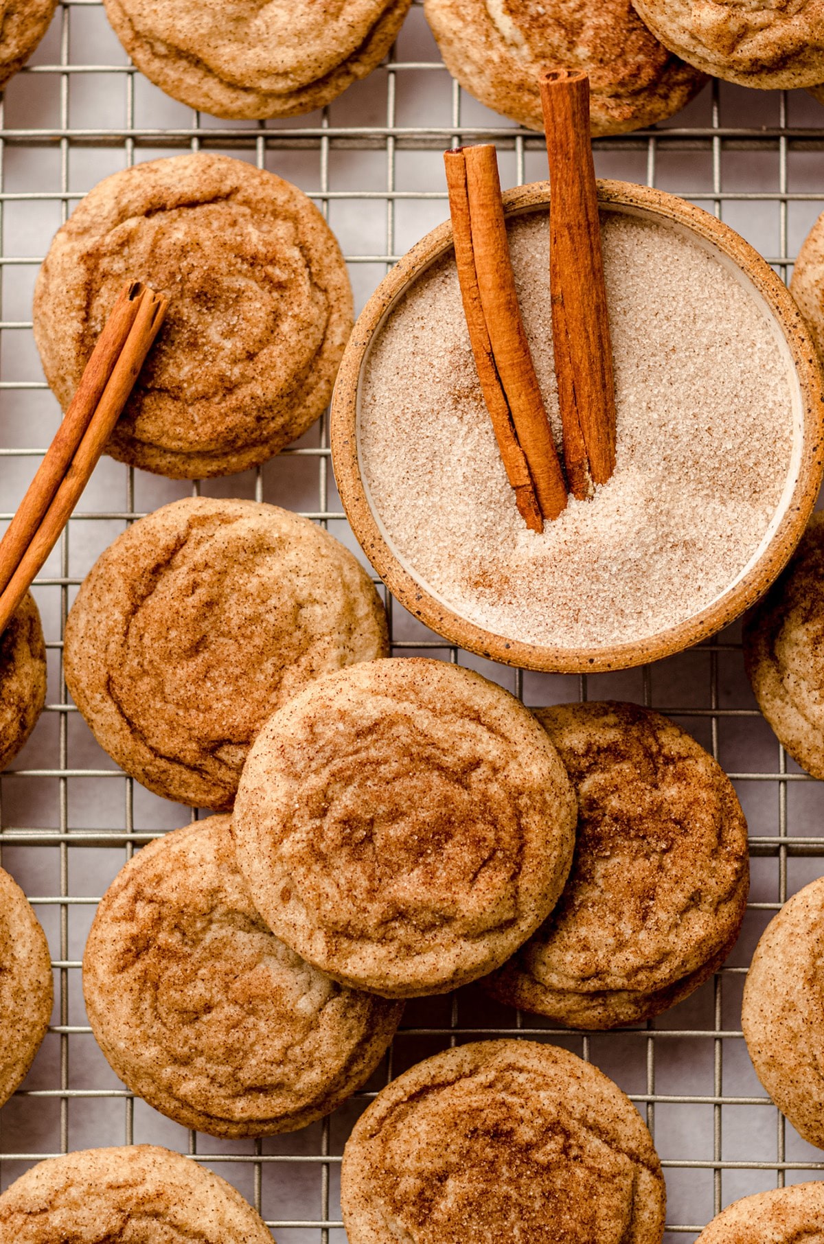 warm snickerdoodle cookies on a cooling rack with a dusting of cinnamon sugar