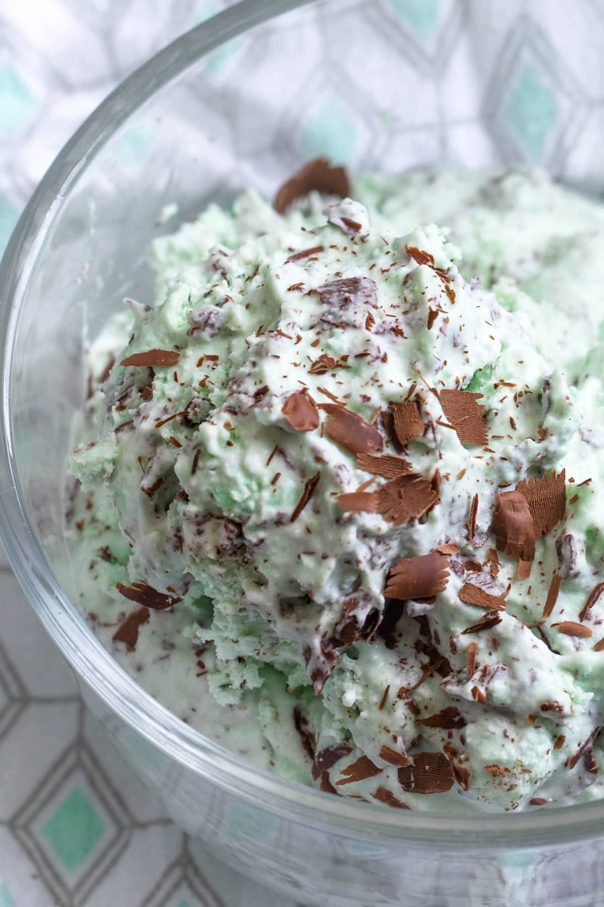 homemade mint chocolate chip ice cream in a glass bowl with dark chocolate shavings