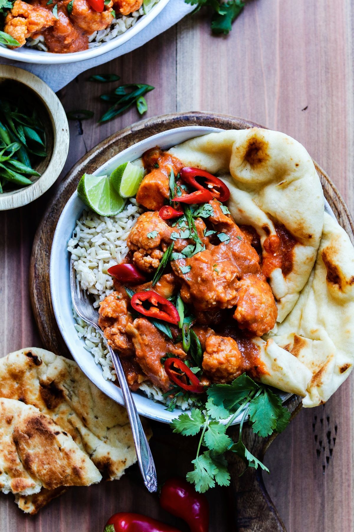 vibrant butter chicken simmering in a slow cooker, naan bread, rice, cilantro garnish