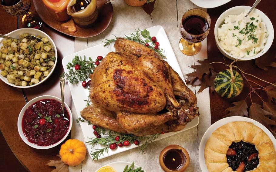 golden brown whole roasted turkey with rosemary and cranberries, rustic table setting
