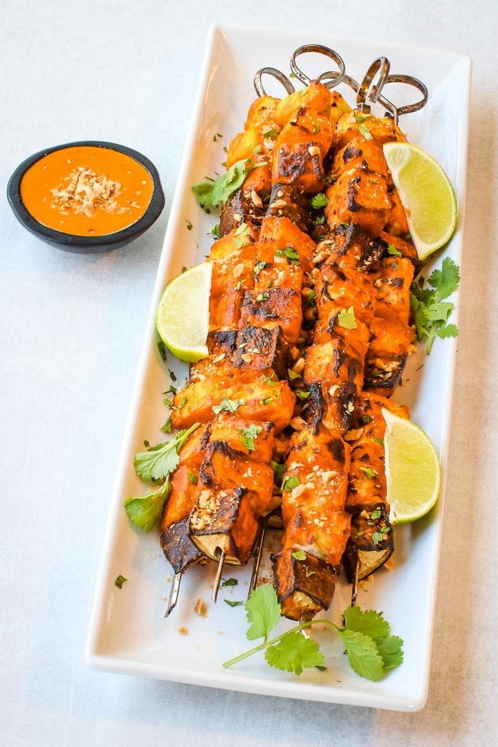 yellow curry vegetable skewers being grilled, drizzled with peanut sauce