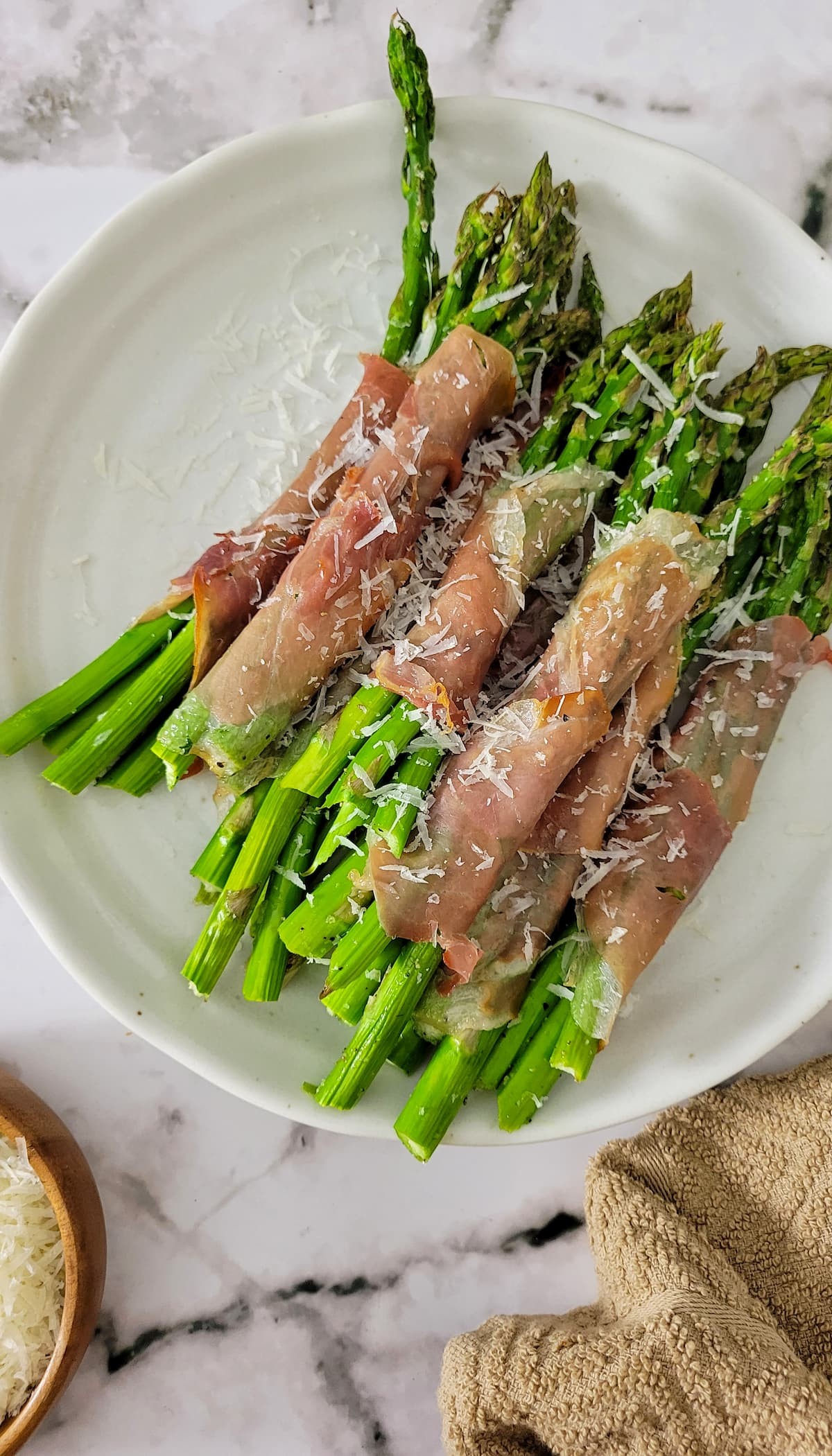 Deliciously crisp prosciutto wrapped asparagus bundles on a rustic cutting board
