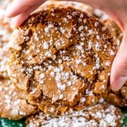 Close-up of a stack of chewy ginger snap cookies dusted with powdered sugar on a festive holiday platter